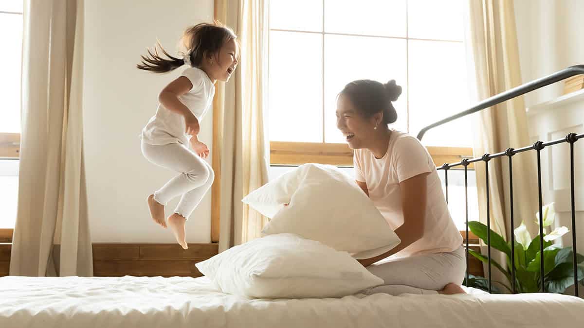 Mother and daughter sitting and jumping on a bed