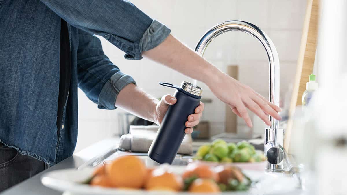 Person using a sink faucet to fill up a water bottle