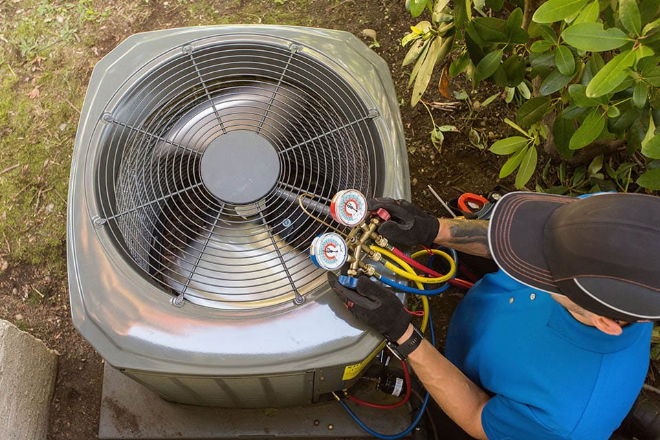 An HVAC technician performing a test on an air conditioner unit