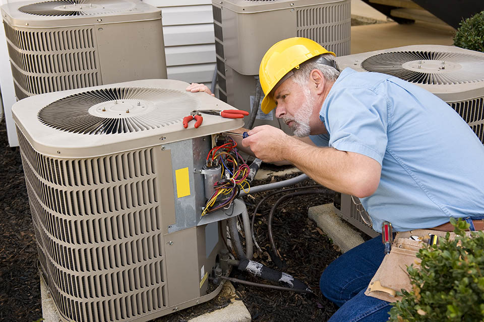HVAC technician repairing air conditioning unit at an apartment complex