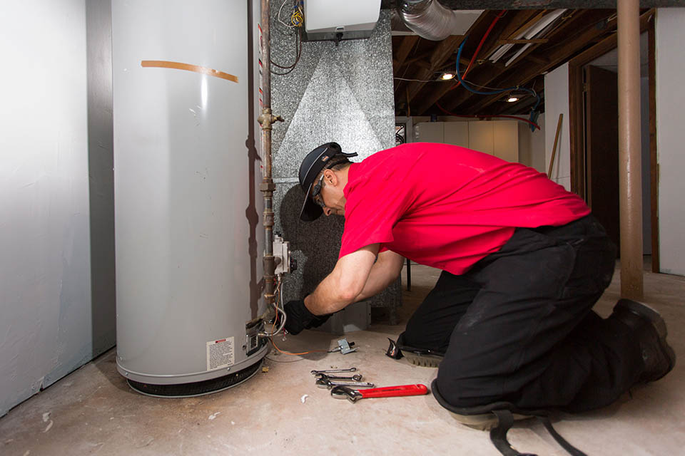 Service technician performing water heater repair service on a tank water heater